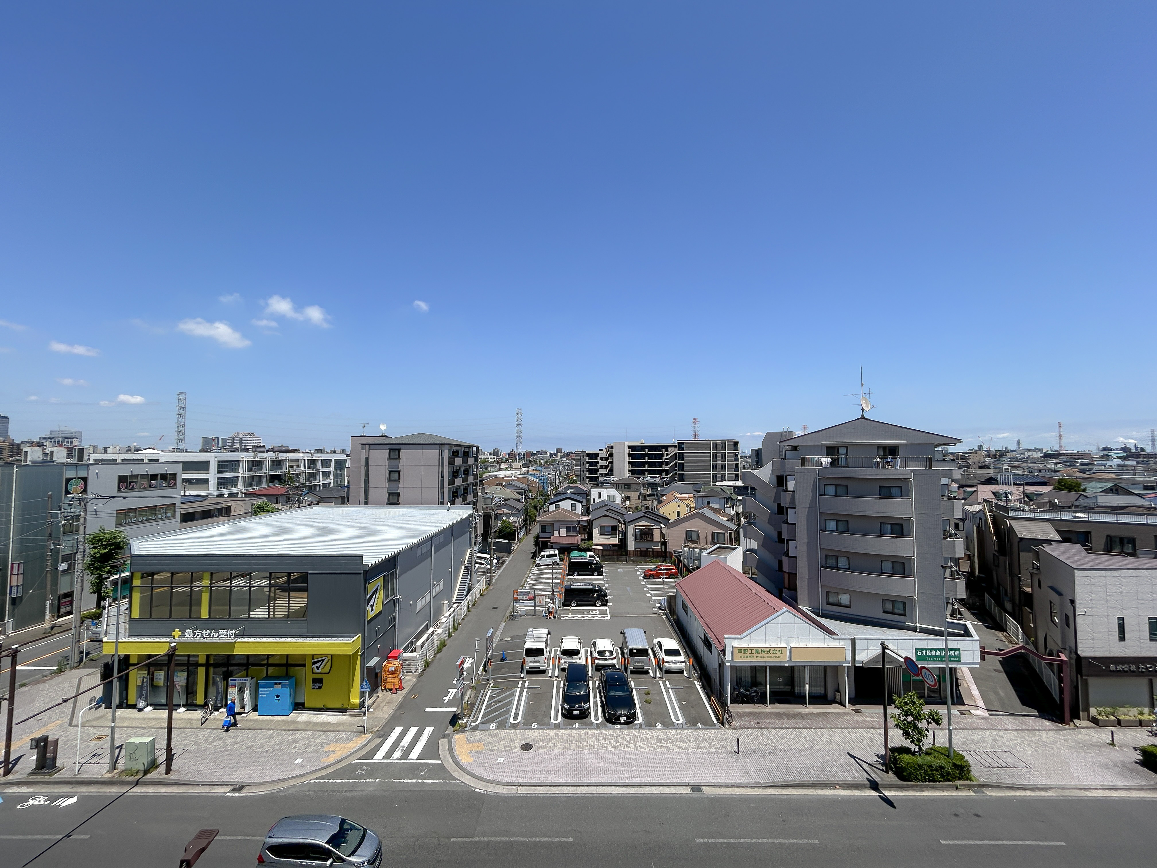 周辺環境:道路、駐車場、周辺建物を含む広範な街並みを捉えた画像